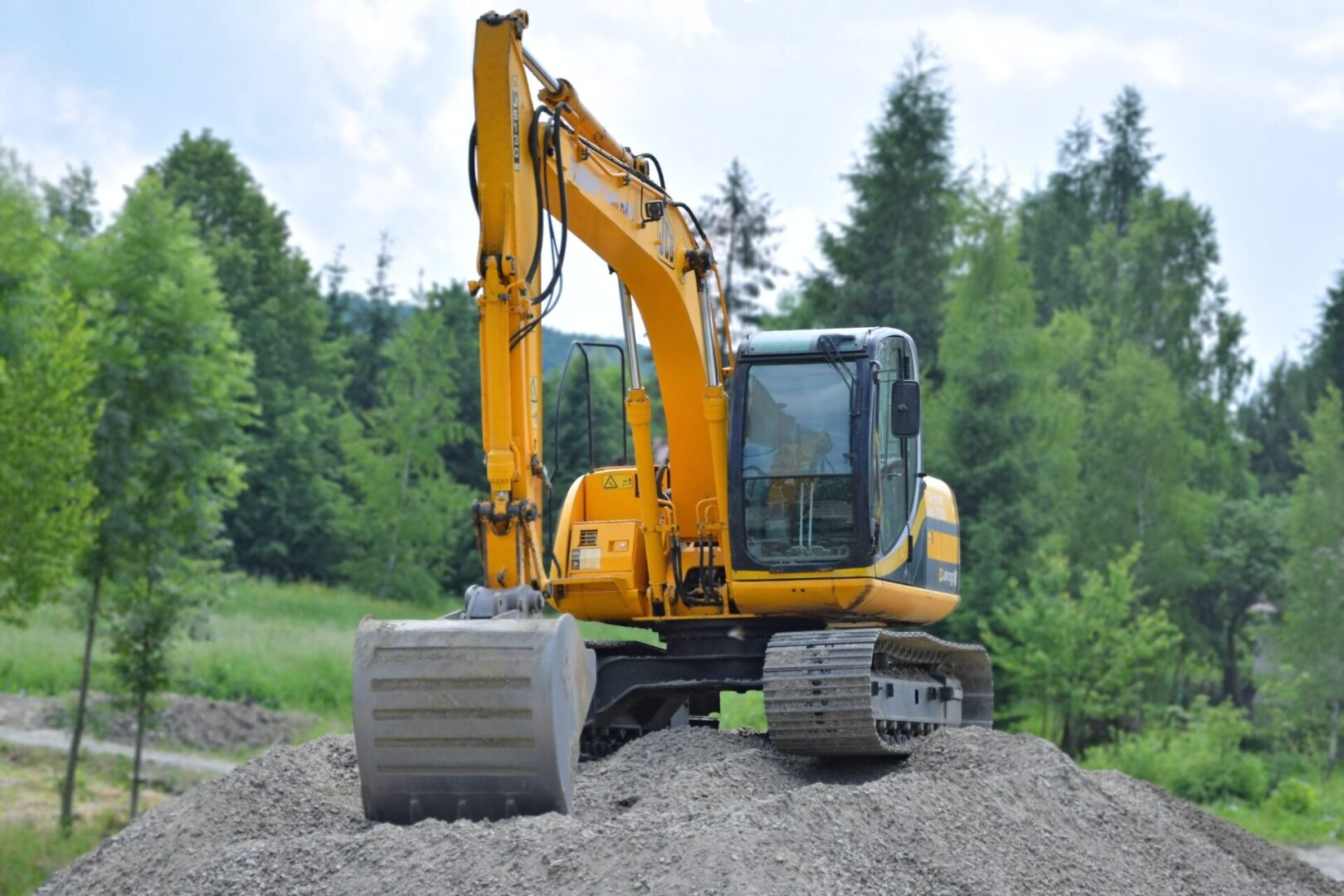 A yellow and black excavator on top of dirt.